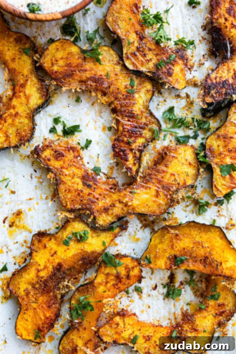 Golden Herb-Cheese Acorn Roast 5 A delectable spread of several roasted acorn squash slices, boasting a golden-crisp cheese coating and delicate herb flecks, showcasing the perfect balance of texture and flavor.