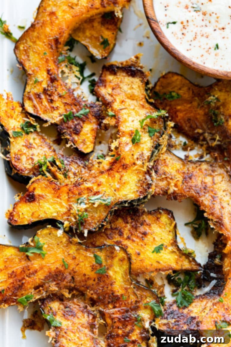 Golden Herb-Cheese Acorn Roast 7 A vibrant collection of golden-brown roasted acorn squash slices, generously coated with crispy melted cheese and fresh herbs, arranged artfully to highlight their inviting textures.