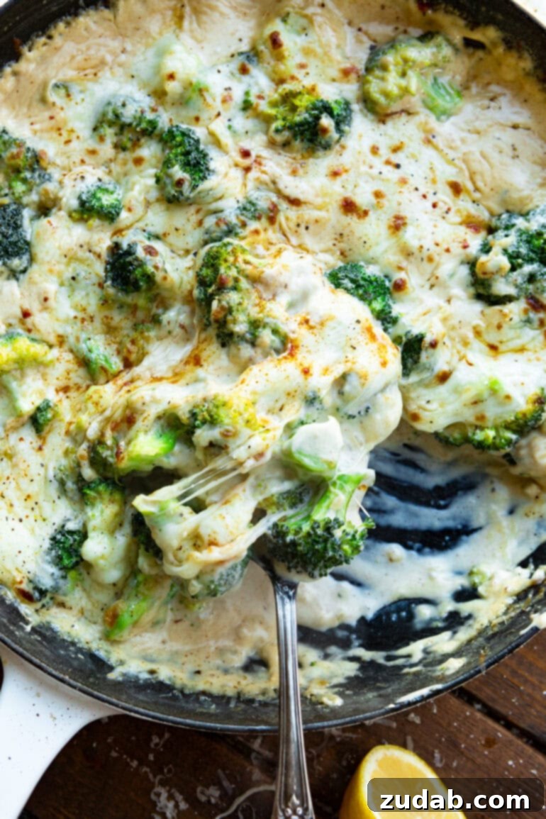 Parmesan Garlic Velvet Broccoli 4 Creamy garlic Parmesan broccoli being stirred gently in a cast iron skillet, showcasing its rich sauce.