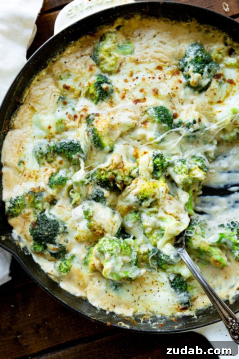 Parmesan Garlic Velvet Broccoli 5 Creamy cheesy broccoli being stirred in a large skillet, showing its rich, thick consistency.