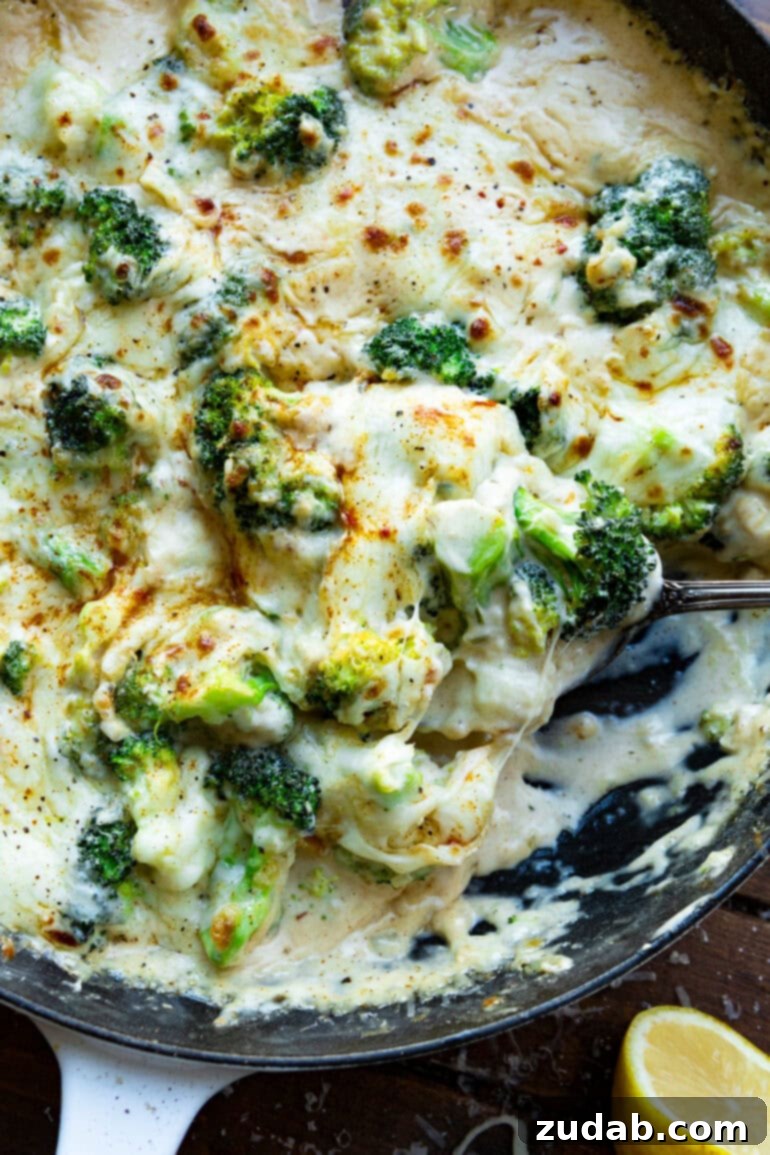 Parmesan Garlic Velvet Broccoli 6 Someone scooping a generous serving of creamy Parmesan garlic broccoli from a large skillet, highlighting its inviting texture.