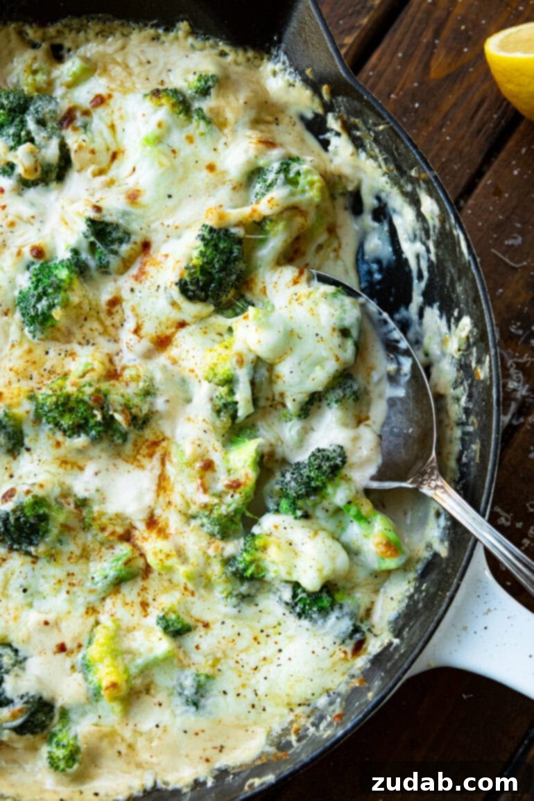 Parmesan Garlic Velvet Broccoli 8 A large metal spoon scooping a generous portion of creamy garlic broccoli from a skillet, ready to serve.