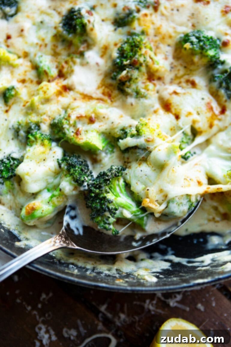 Parmesan Garlic Velvet Broccoli 10 A skillet full of creamy garlic Parmesan broccoli being scooped up by a large silver spoon, ready for serving.