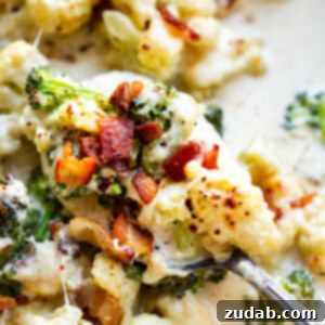 A photo of someone scooping out a bite of creamy garlic parmesan broccoli and cauliflower, showing its delicious texture.