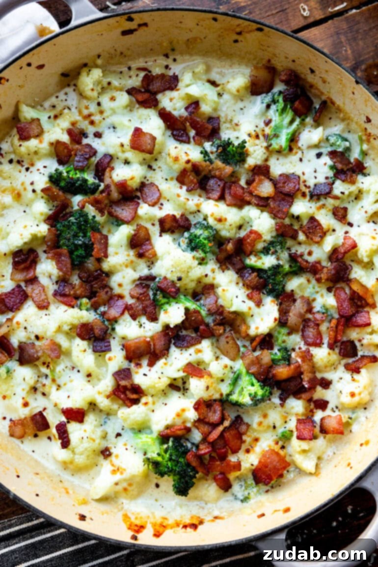 Creamy Garlic Parmesan Broccoli Cauliflower with Crispy Bacon 7 A vibrant, close-up overhead shot of a large cast-iron skillet filled with creamy garlic parmesan broccoli and cauliflower, showcasing the rich, thick sauce coating the vegetables and the perfect golden-brown cheese topping.
