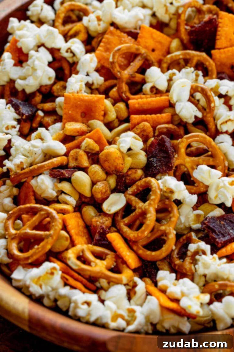 Super Bowl's Ultimate Manly Snack Attack 5 A close-up shot of a richly textured football snack mix in a bowl, showcasing the delicious combination of fluffy popcorn, crisp pretzels, cheesy Cheez-It crackers, savory peanuts, crunchy corn nuts, and chewy beef jerky pieces.