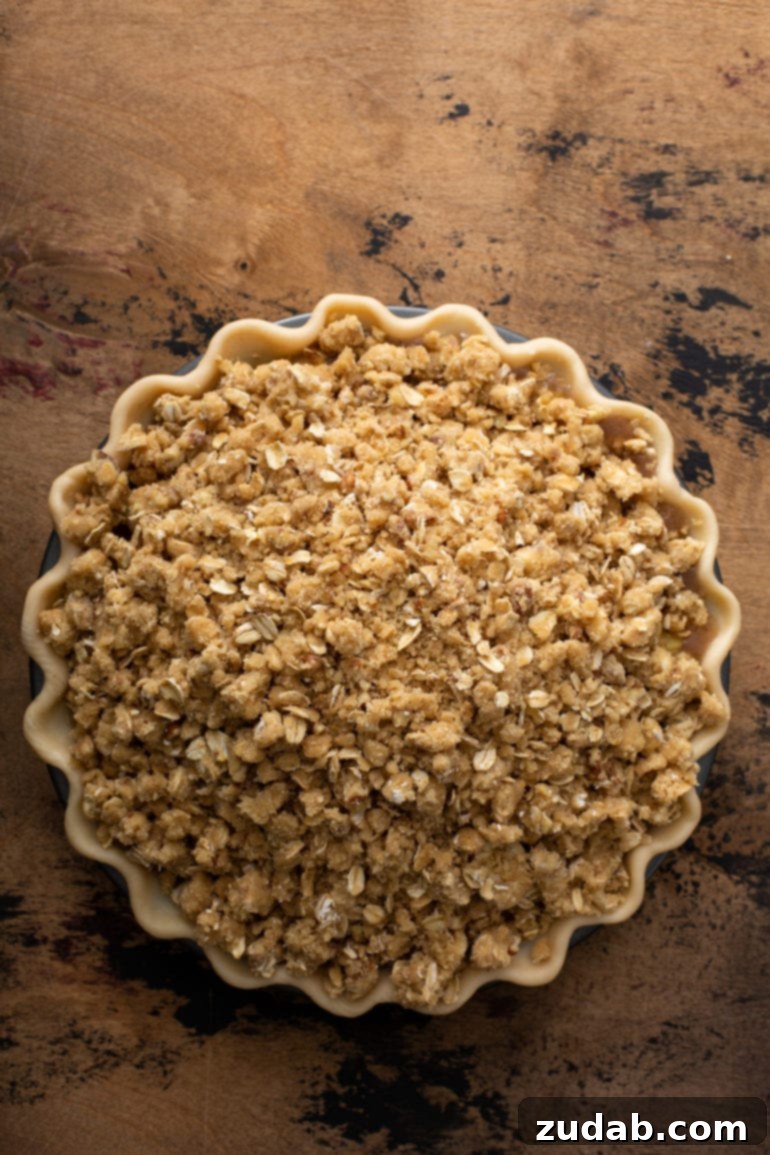 A Dutch Apple Pie, ready to be baked, with its top generously covered in a nutty, golden-brown streusel crumble.