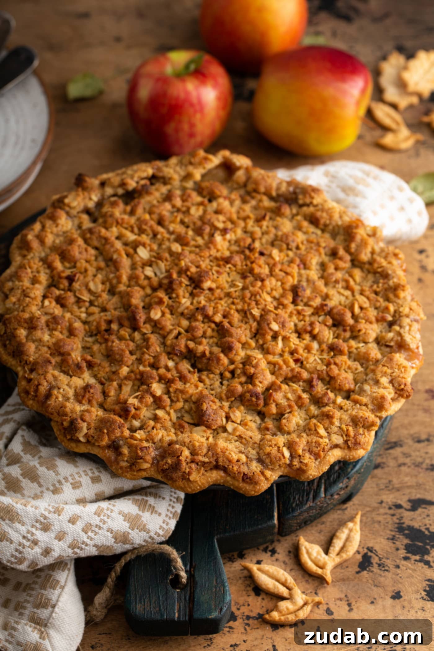 A beautifully baked Dutch Apple pie with a golden-brown streusel topping, resting on a crisp white tea towel, showcasing its inviting texture.