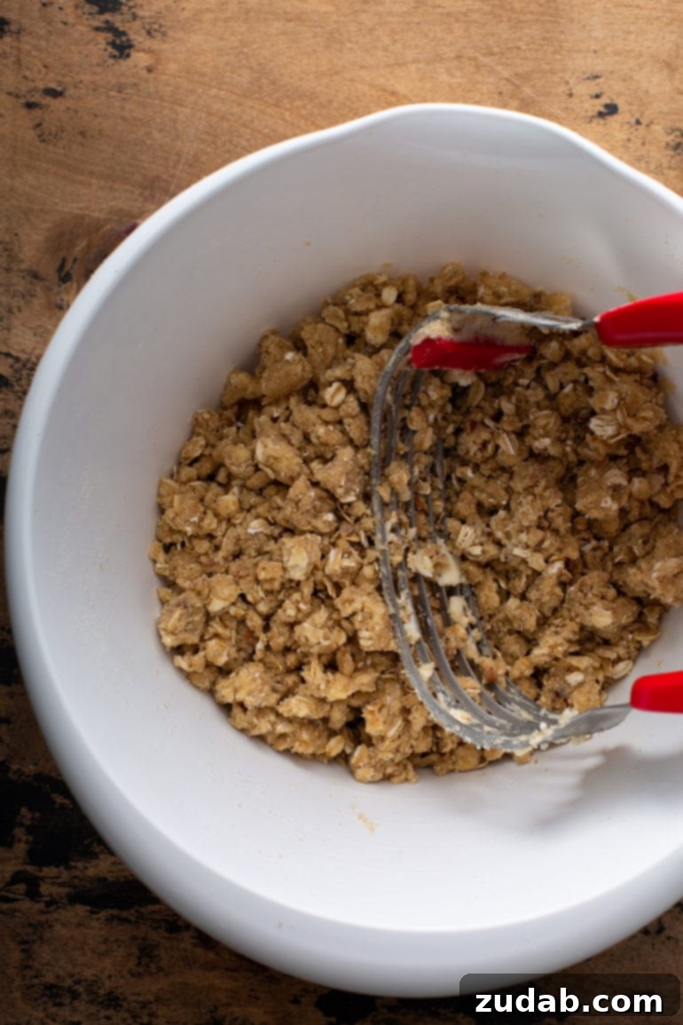 A bowl of Dutch Apple Pie topping ingredients, being mixed together with a pastry cutter to create a perfectly crumbly texture.