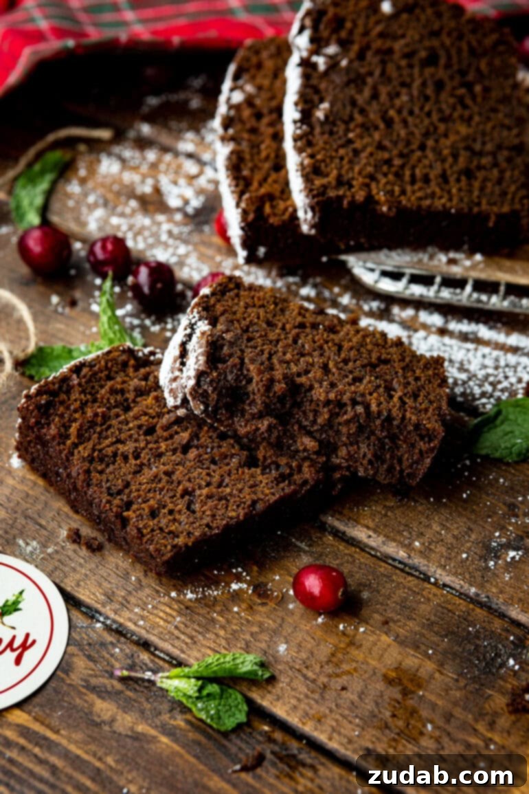 Warm Spiced Gingerbread Loaf 11 Two slices of gingerbread loaf positioned in front of a whole loaf, all on a rustic table.