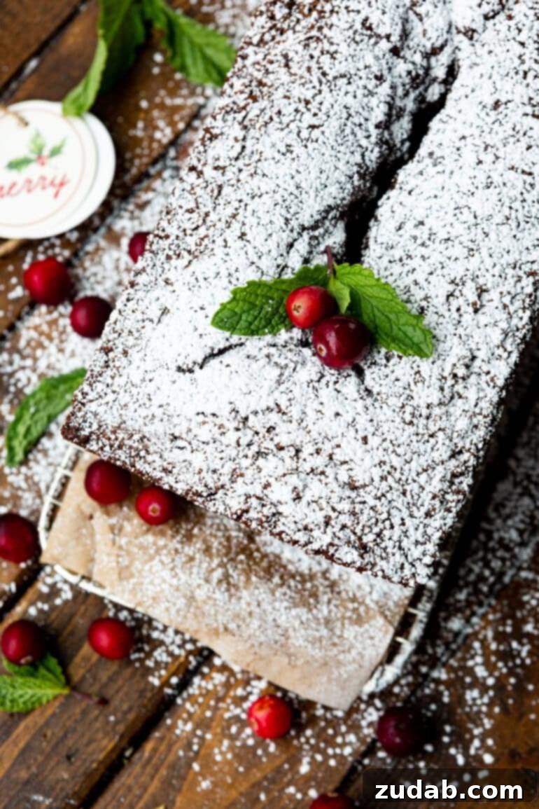 Warm Spiced Gingerbread Loaf 3 A gingerbread loaf, beautifully dusted with powdered sugar and adorned with two whole cranberries and greenery from an overhead perspective.