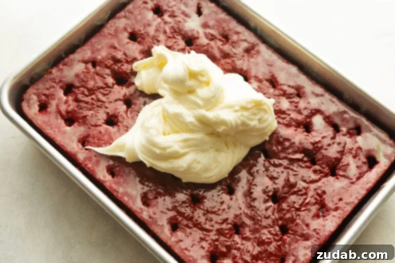 The Ultimate Red Velvet Poke Cake: Foolproof & Delicious 4 Cream Cheese Frosting being spread on a Red Velvet Poke Cake