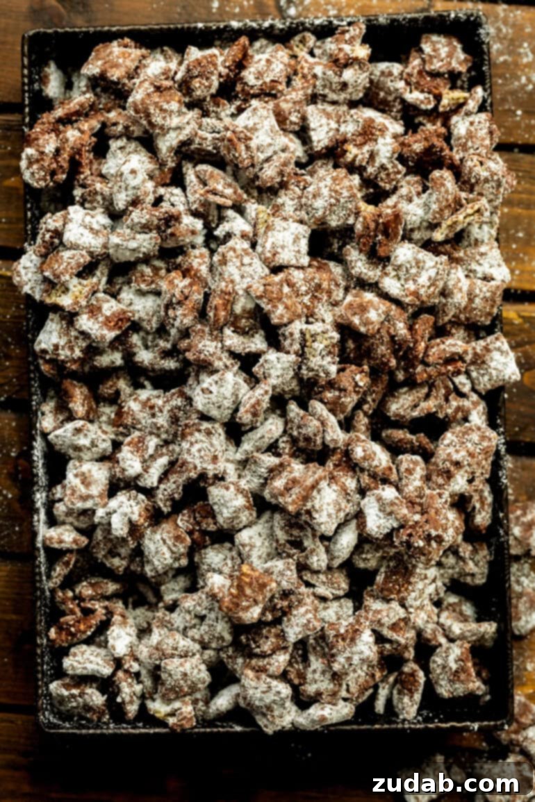 Decadent Dark Chocolate Peanut Butter Muddy Buddies 3 a baking sheet full of dark chocolate muddy buddies mix coated in powdered sugar