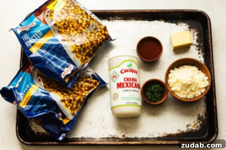 Oven Baked Sheet Pan Mexican Street Corn 3 A vibrant flat lay photo showcasing all the fresh ingredients for creamy Mexican street corn, including bags of frozen corn, a bottle of Mexican crema, chili powder, and crumbled cotija cheese, ready for preparation.