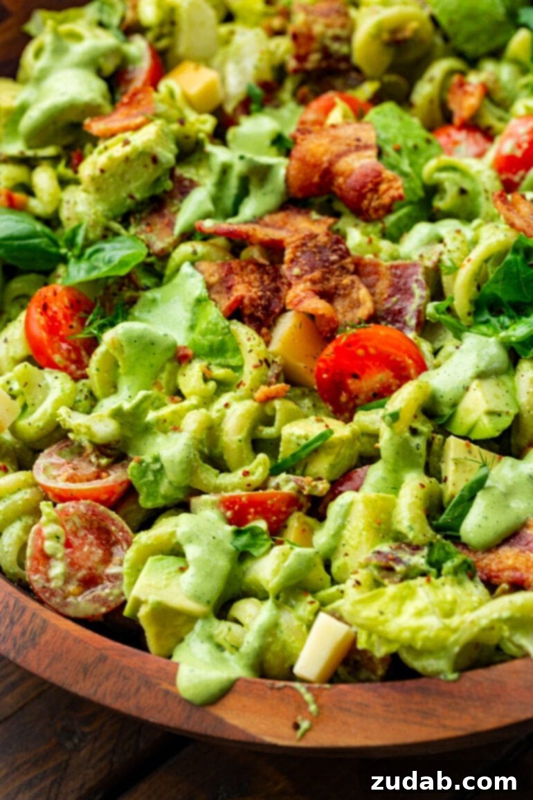 BLT Pasta Perfection 3 A close-up view of creamy BLT pasta salad, highlighting crispy bacon pieces, halved cherry tomatoes, chopped romaine lettuce, and radiatore pasta.