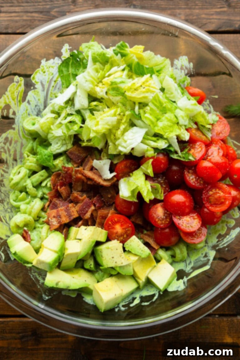 BLT Pasta Perfection 7 Step 3: Tossing the pasta and cheese with the creamy dressing in a large bowl, followed by the fresh BLT ingredients.