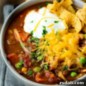 A bowl of taco stew with sour cream, cheese and Fritos