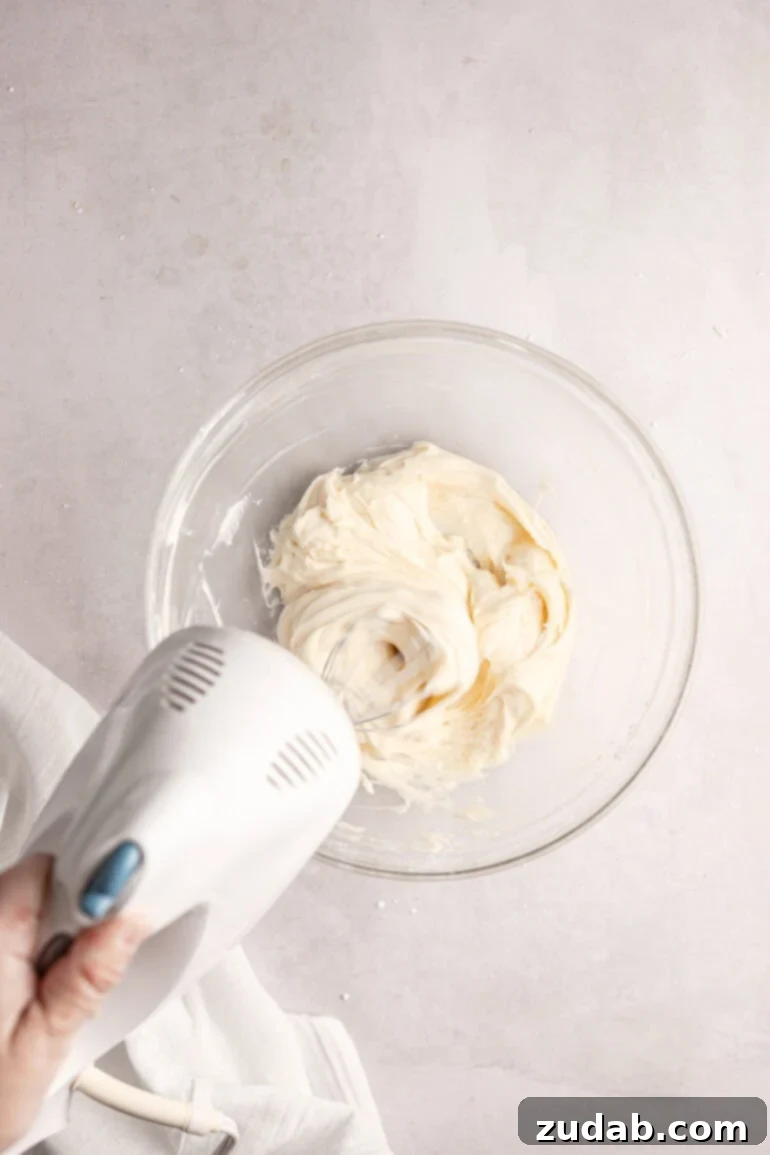 Light and Fluffy Cream Cheese Frosting 6 Step-by-step image showing the cream cheese mixture being beaten until smooth and lump-free.