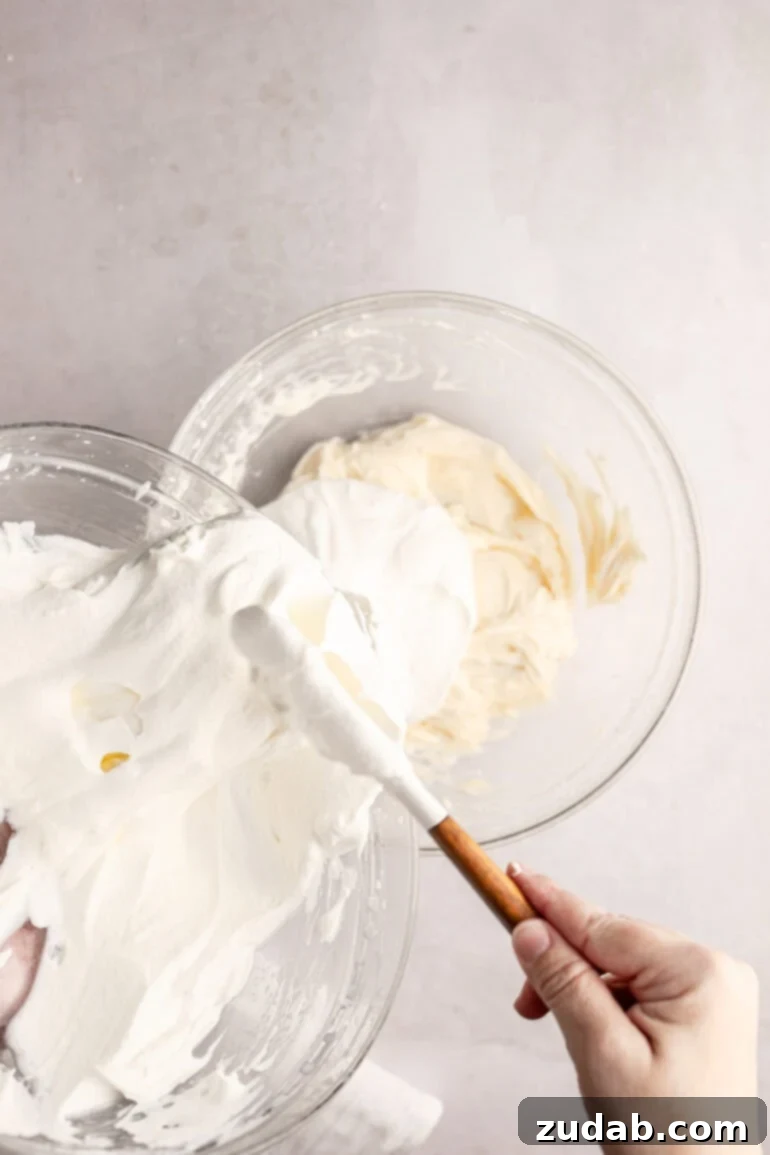 Light and Fluffy Cream Cheese Frosting 7 Step-by-step image showing the fluffy whipped cream being added to the smooth cream cheese mixture.