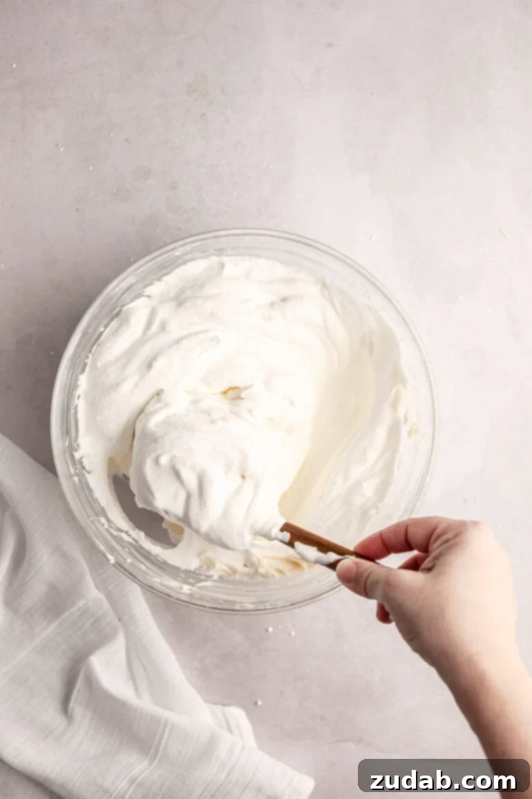 Light and Fluffy Cream Cheese Frosting 8 Step-by-step image showing the gentle folding process, combining the whipped cream and cream cheese mixtures.