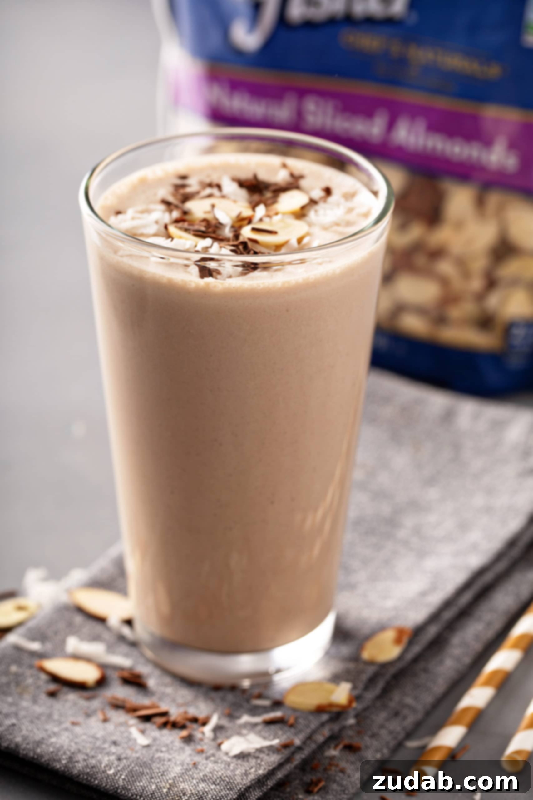 Coconut Almond Bliss Protein Shake 8 A tall glass of almond joy protein shake with sliced almonds on top.