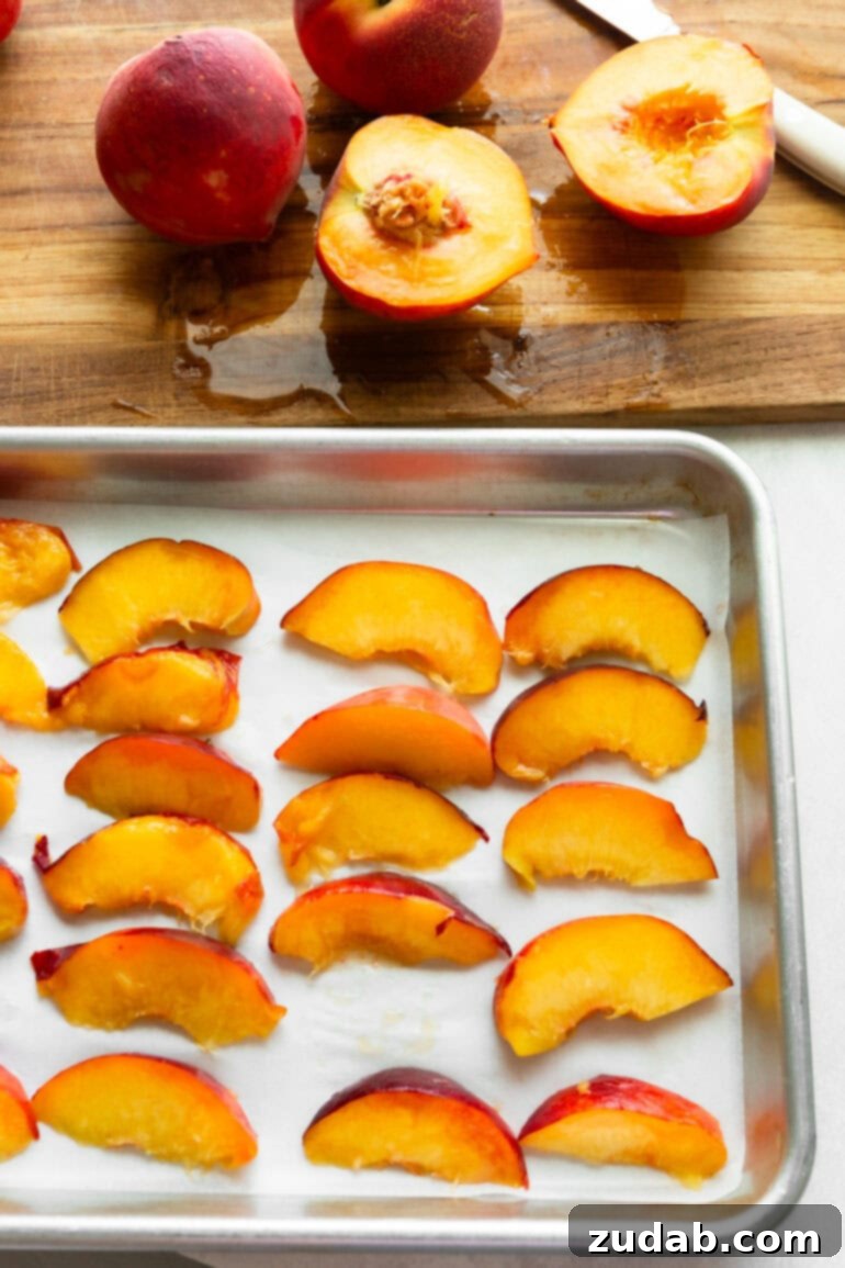 Freeze Peaches Perfectly Every Time 5 Halved and sliced peaches arranged on a parchment-lined baking sheet before freezing.