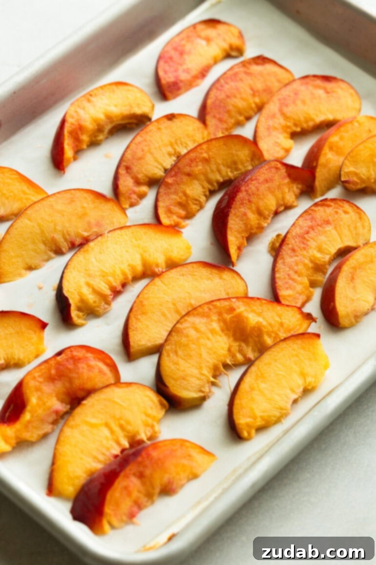 Freeze Peaches Perfectly Every Time 6 Close-up of evenly spaced peach slices on a baking sheet, prepped for flash-freezing.