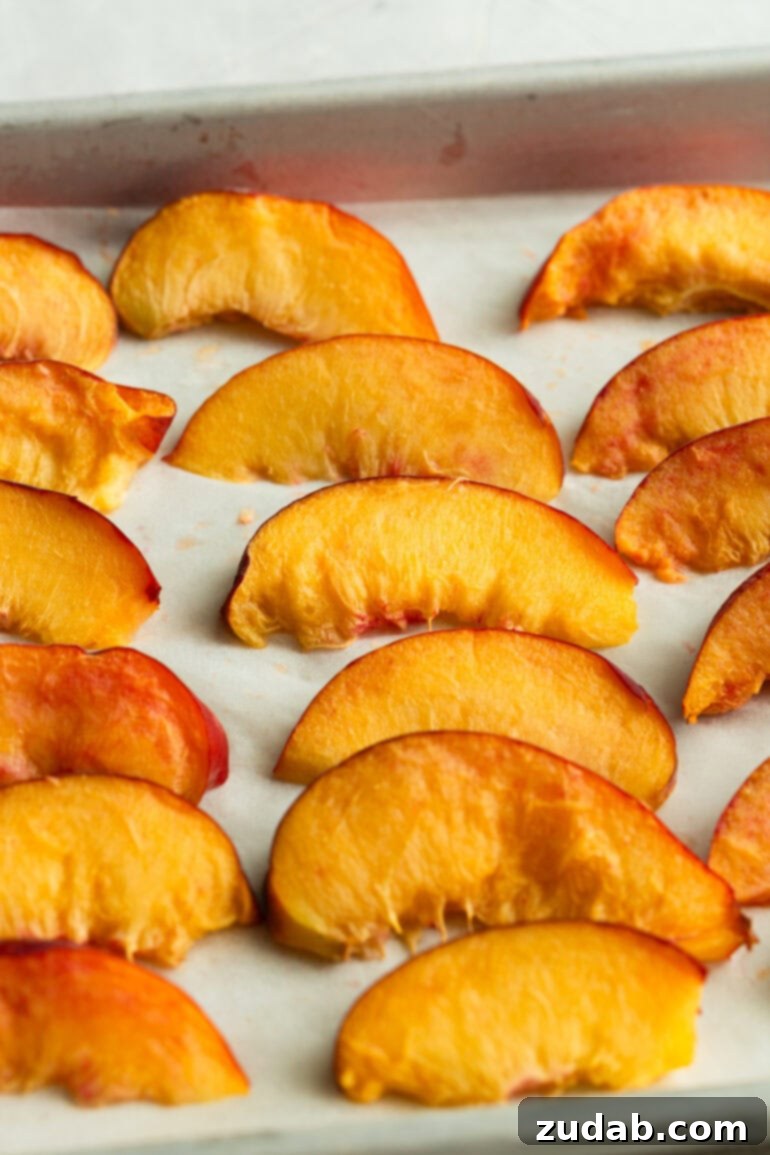 Freeze Peaches Perfectly Every Time 7 Frozen peach slices on a baking sheet, slightly frosty and ready to be transferred to storage.