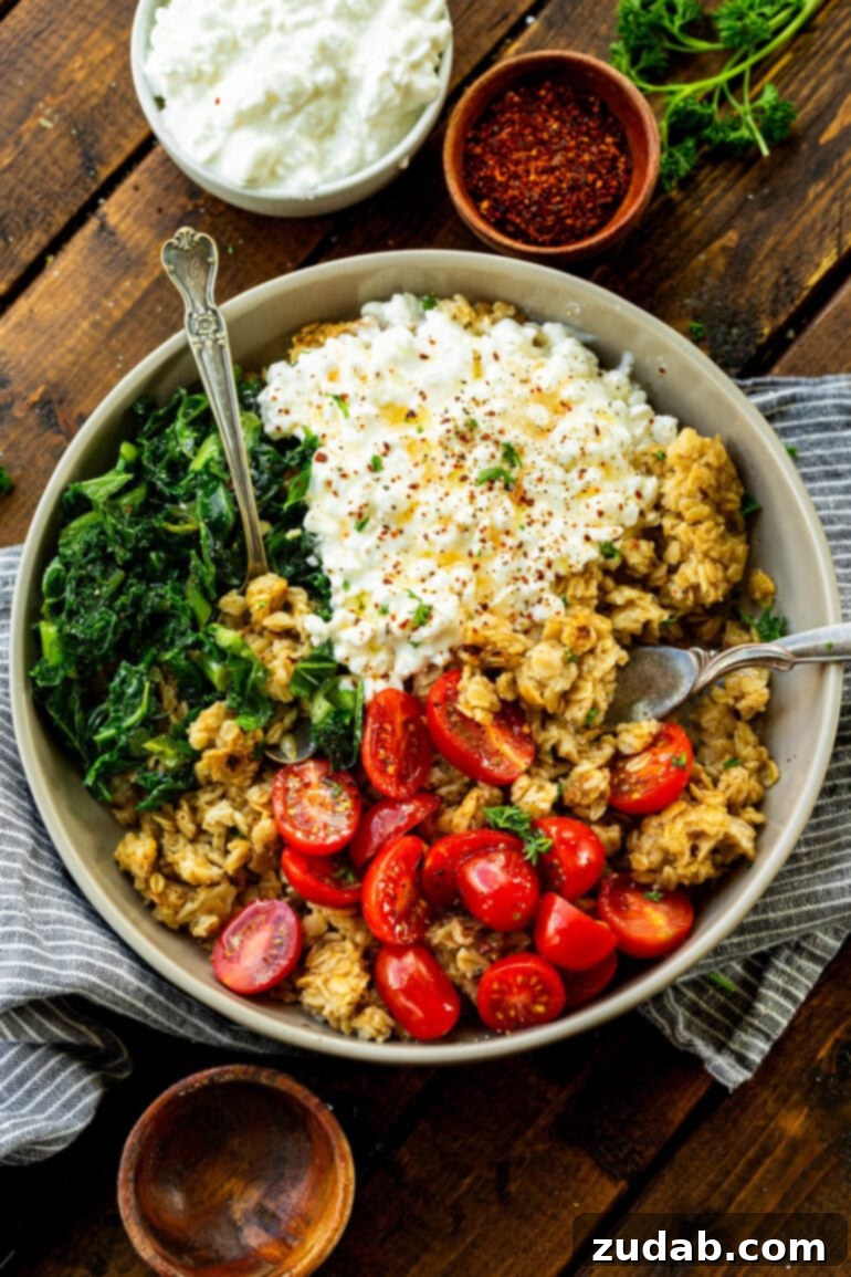 7 Minute High Protein Savory Cottage Cheese Oats 5 a photo of a bowl of savory oats mixed with cottage cheese, cherry tomatoes, chopped kale and two forks in it ready to stir it all together
