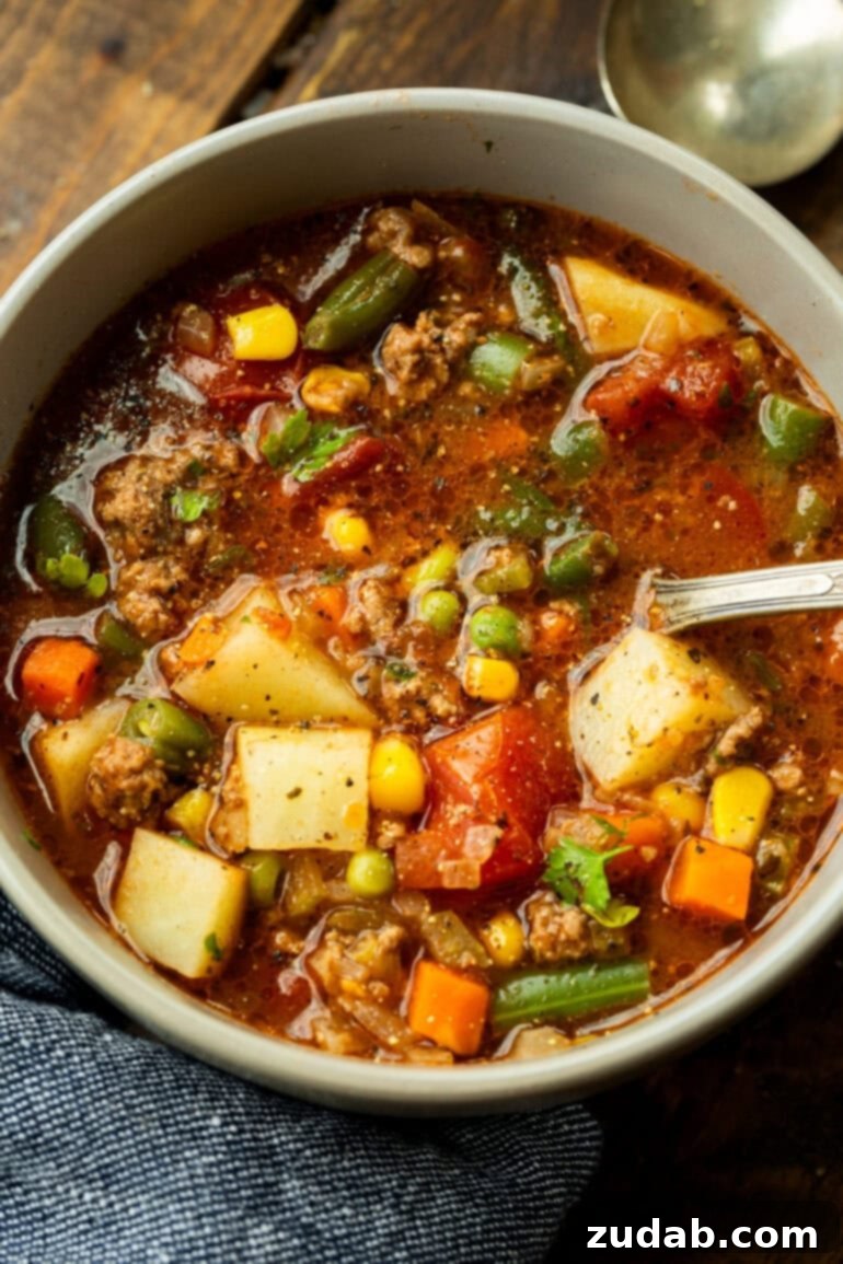 Quick and Easy Ground Beef Vegetable Soup 5 A steaming bowl of ground beef vegetable soup with a spoon, showing the rich broth, chunks of beef, and colorful vegetables, ready to be enjoyed.