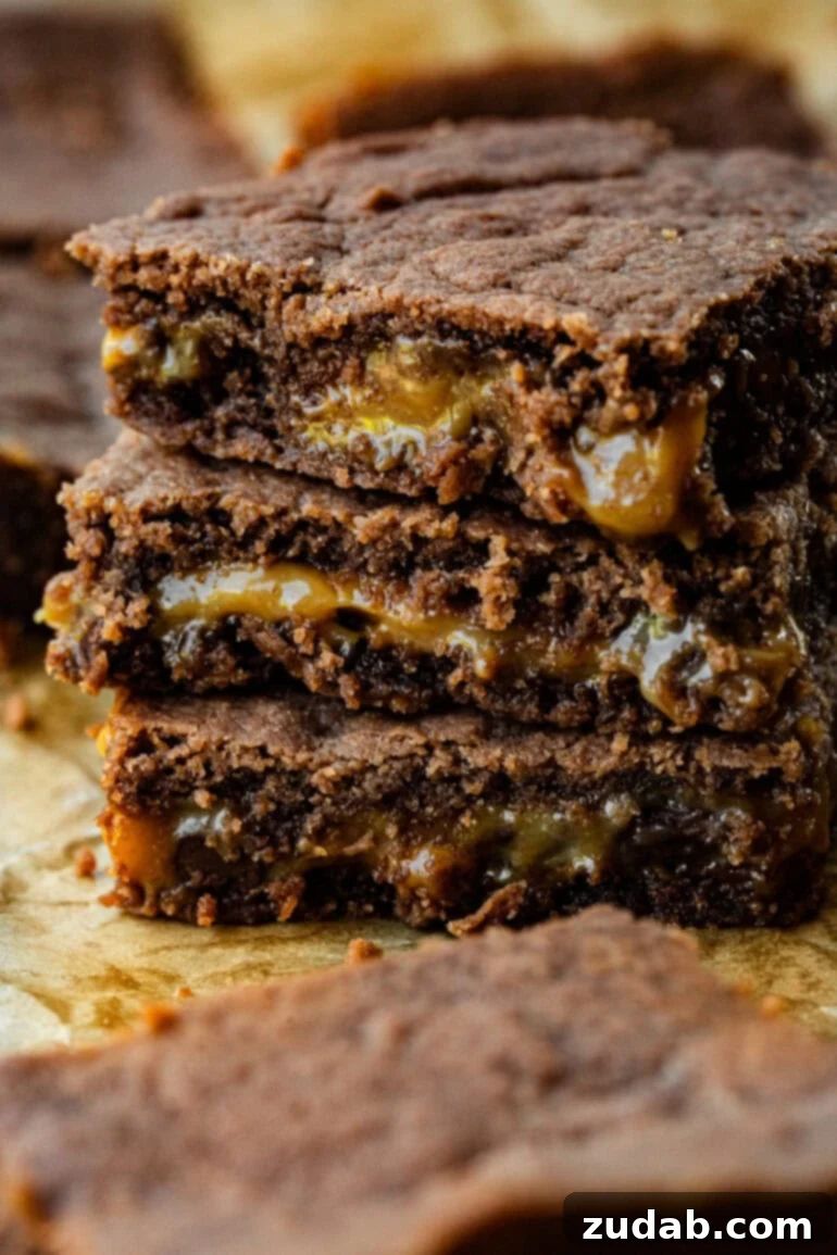 Moms Fudgy Caramel Brownies 2 A stack of brownies with each with a gooey layer of caramel.