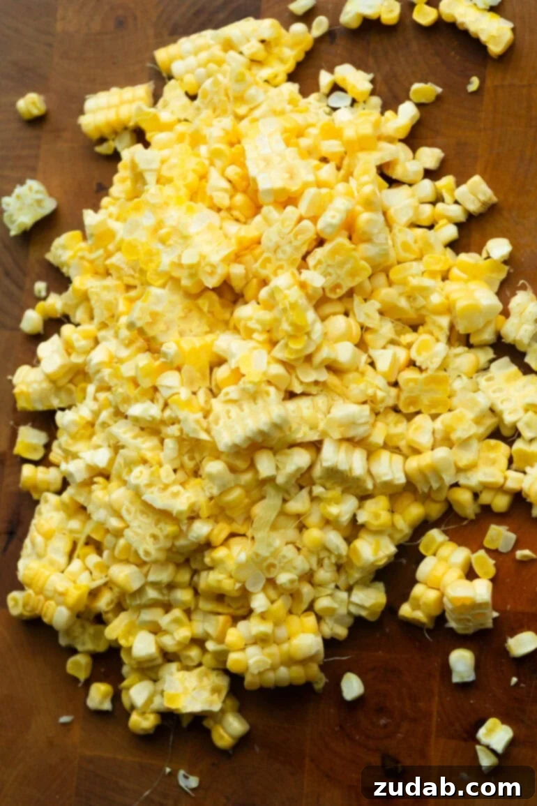 Preparing Fresh Corn for Creamed Corn Freshly cut corn kernels on a wooden cutting board, ready for cooking.