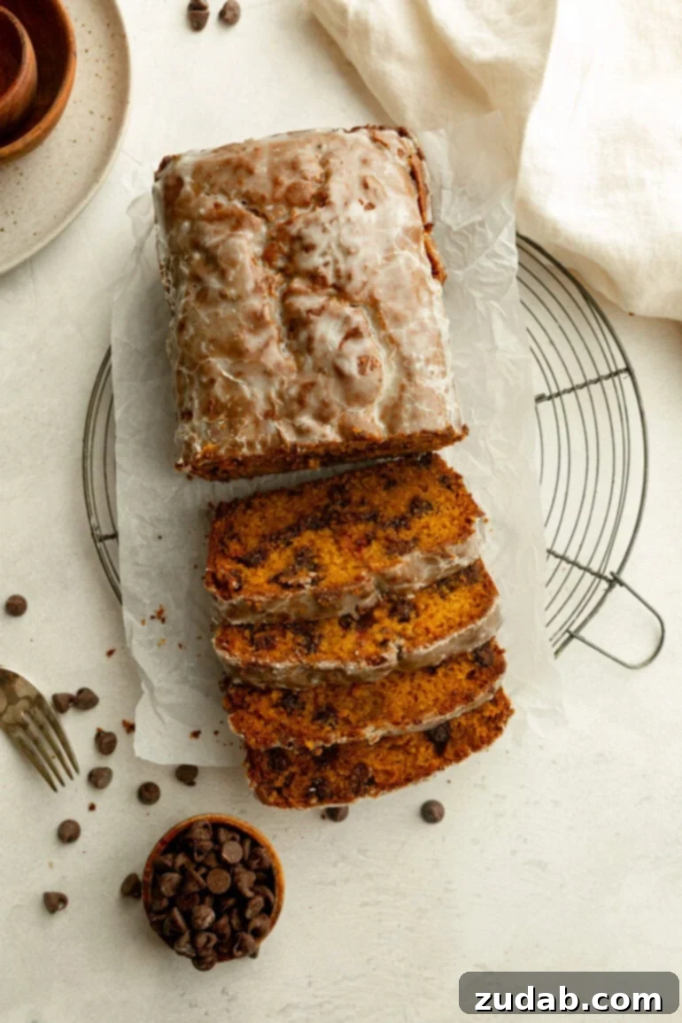 Heavenly Pumpkin Chocolate Chip Loaf 3 A half-sliced loaf of glazed pumpkin bread with chocolate chips, ready to be served.