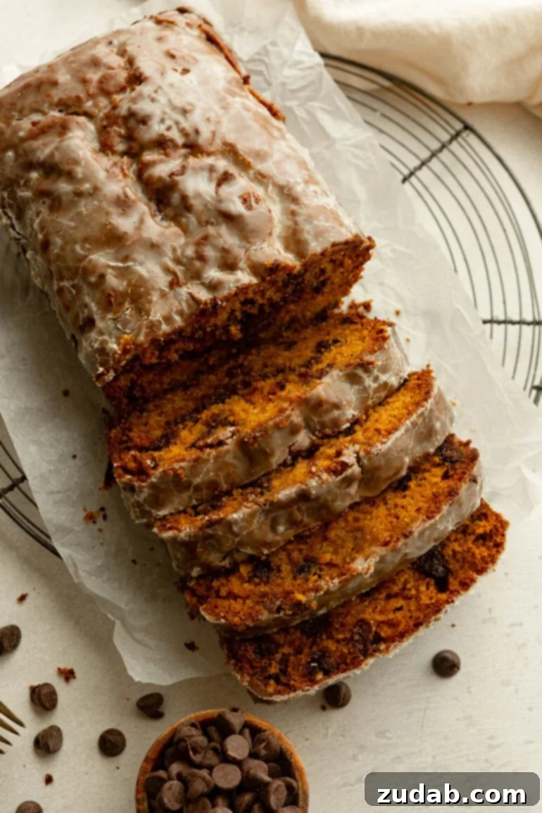 Heavenly Pumpkin Chocolate Chip Loaf 4 A glistening loaf of glazed pumpkin chocolate chip bread on parchment paper, ready to be enjoyed.