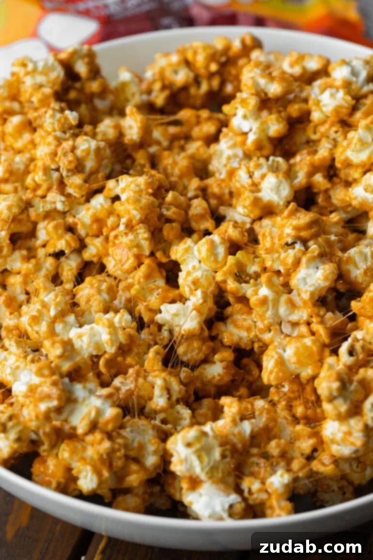 Cozy Fall Snack: Pumpkin Marshmallow Popcorn 4 A close-up shot of gooey pumpkin spice marshmallow coated popcorn, highlighting its festive texture and inviting autumn colors.