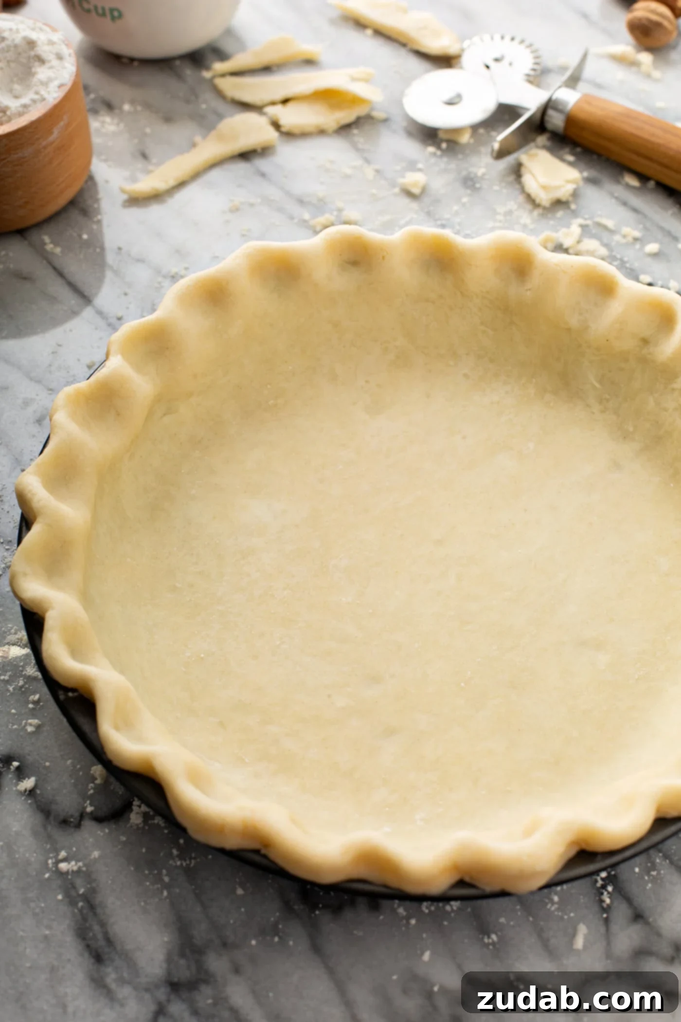 My Absolute FAVORITE Pie Crust Recipe A photo of an uncooked butter pie crust in a pie tin sitting on a table.