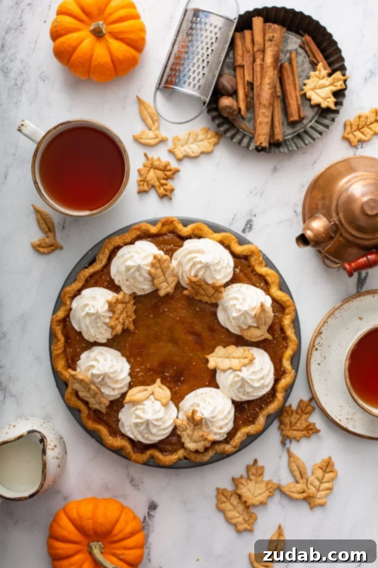 Pure Pumpkin Pie: Easy Homemade Bliss 8 A photo of a pumpkin pie topped with piped whipped cream and stamped pie crust leaves taken from above.
