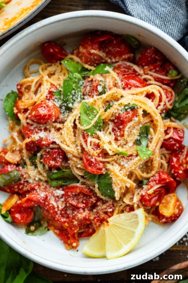 Quick and Easy 20-Minute Tomato Basil Angel Hair Pasta 2 a photo of an italian dish with fresh basil, sauteed cherry tomatoes and a slice of lemon on the side