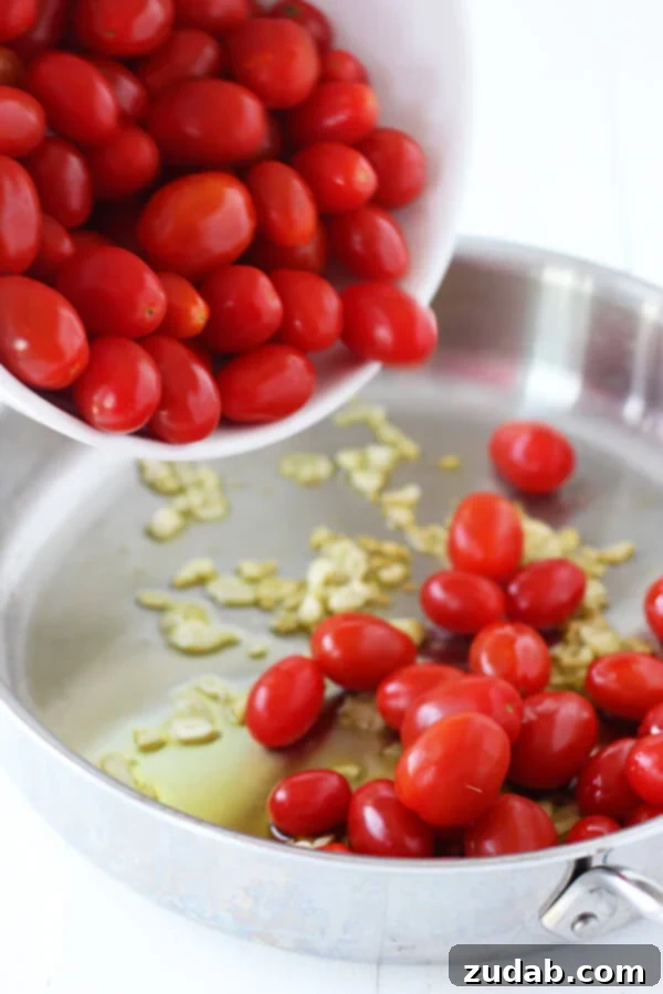 This 20 Minute Cherry Tomato and Basil Angel Hair Pasta comes together in a jiffy, and will satisfy the whole family, even the kids! tomatoes being tossed into a pan with garlic and olive oil