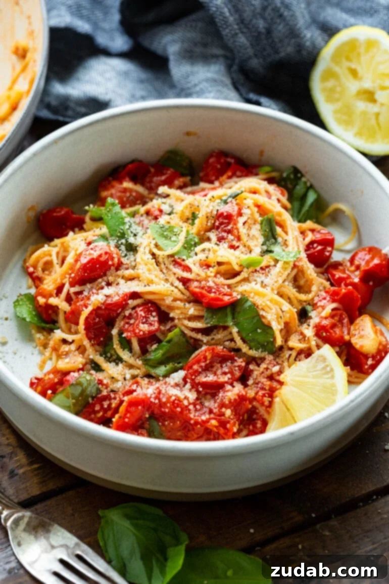 Quick and Easy 20-Minute Tomato Basil Angel Hair Pasta 3 a photo of a bowl of cooked angel hair pasta toss with sauteed cherry tomatoes, fresh basil and a slice of fresh lemon.