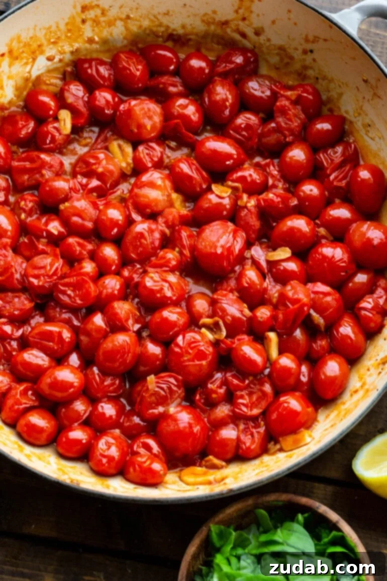 Quick and Easy 20-Minute Tomato Basil Angel Hair Pasta 5 a photo of a pot full of cherry tomatoes being sauteed with sliced fresh garlic