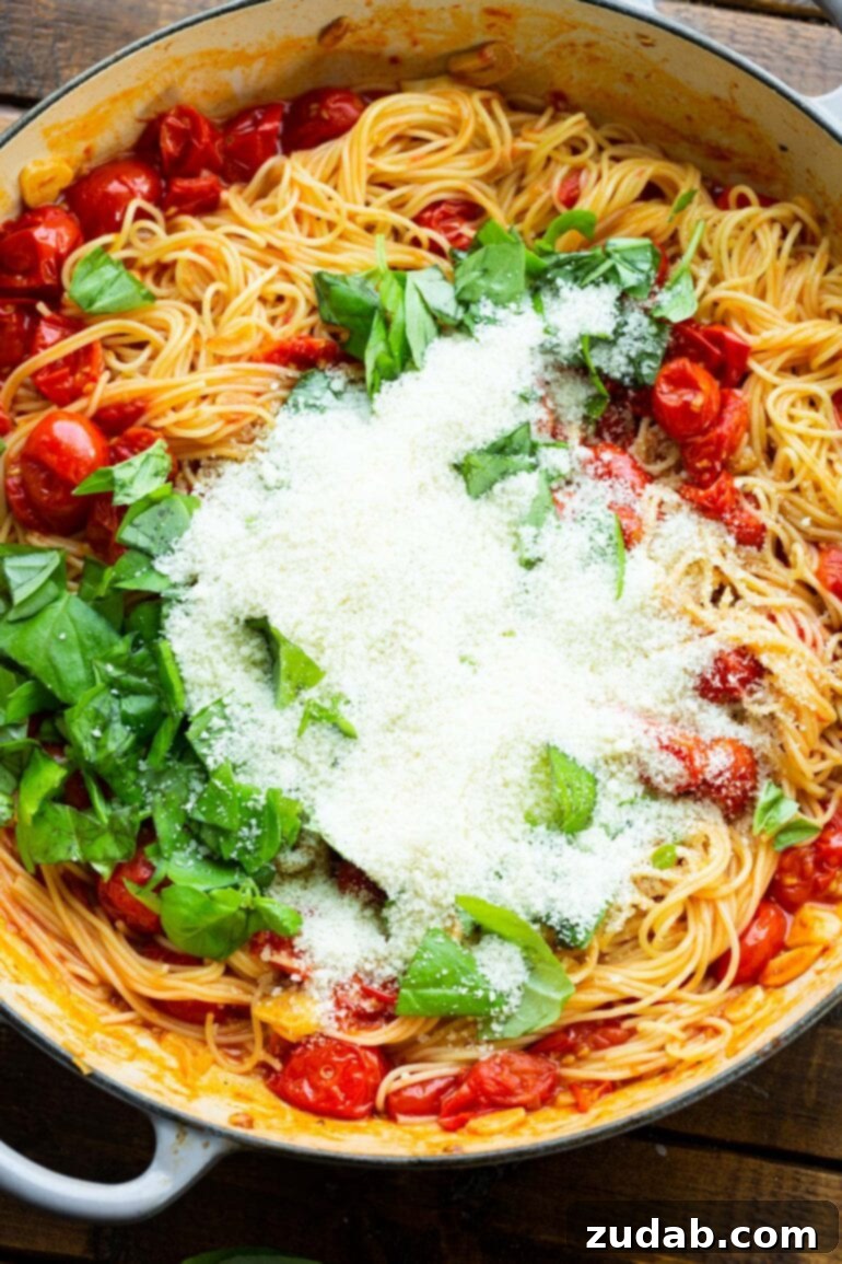 Quick and Easy 20-Minute Tomato Basil Angel Hair Pasta 7 a photo of cooked angel hair pasta topped with sauteed grape tomatoes, fresh basil leaves and granulated parmesan cheese