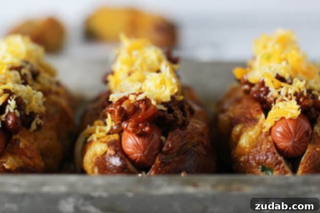 The Ultimate Chili Cheese Pretzel Hot Dog A fully assembled Jalapeño and Cheddar Pretzel Hot Dog with Turkey Chili Cheese, showcasing the melted cheese and vibrant toppings.