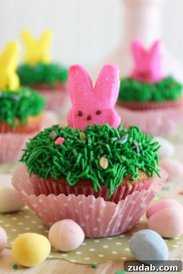 Festive Easter Bunny Cupcakes A close-up shot of a single Cadbury Mini Egg Cupcake with a festive bunny Peep decoration, highlighting the vibrant green frosting.