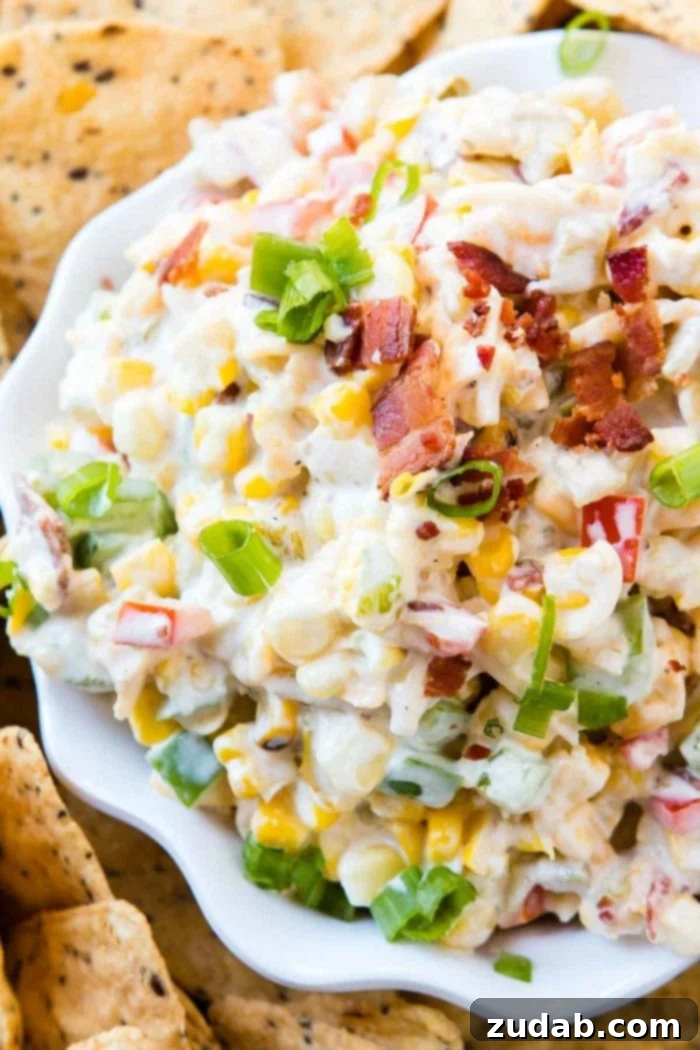 The Ultimate Cheesy Bacon Ranch Corn Dip 2 Overhead view of a creamy, cheesy bacon ranch corn dip in a white serving dish, surrounded by golden tortilla chips, ready to be enjoyed.