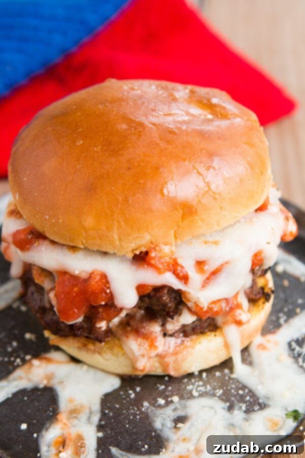 Ricotta, sauce, and mozzarella layered on Italian beef for Lasagna burgers! Bring on summer! ohsweetbasil.com Delicious lasagna burger with layers of ricotta, sauce, and mozzarella on an Italian beef patty, served on garlic bread buns. Perfect for summer grilling!