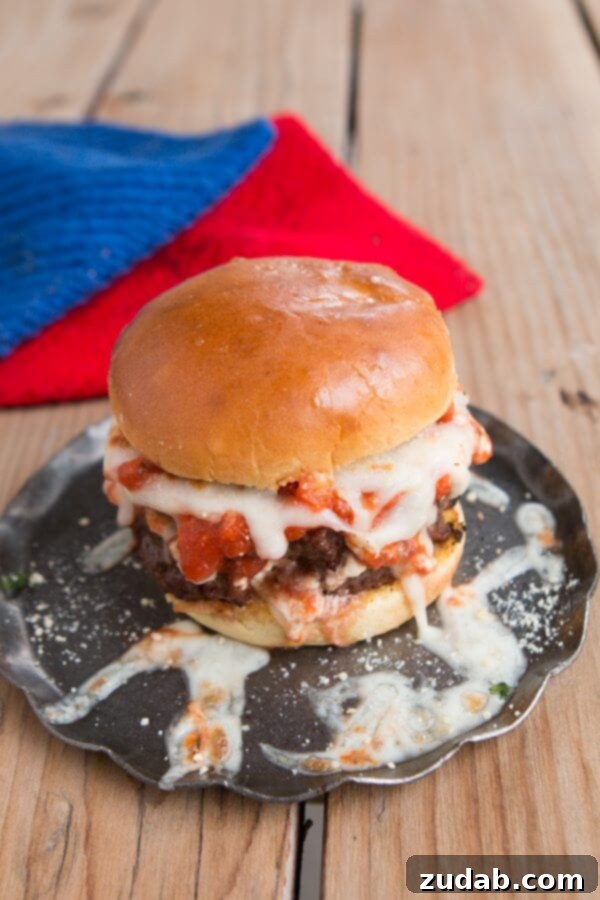 ricotta, sauce, and mozzarella layered on italian beef for Lasagna burgers! Bring on summer! ohsweetbasil.com A vibrant Lasagna Burger, showcasing the exquisite layering of seasoned beef, creamy ricotta, rich marinara, and melted mozzarella, all on a toasted garlic bun.