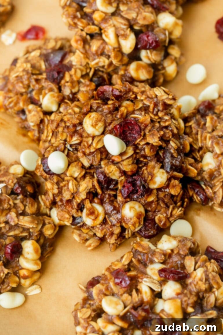 Spiced White Chocolate Cranberry Breakfast Cookies 9 A rustic wooden tray filled with an assortment of perfectly baked oatmeal breakfast cookies, generously embellished with craisins and white chocolate chips.