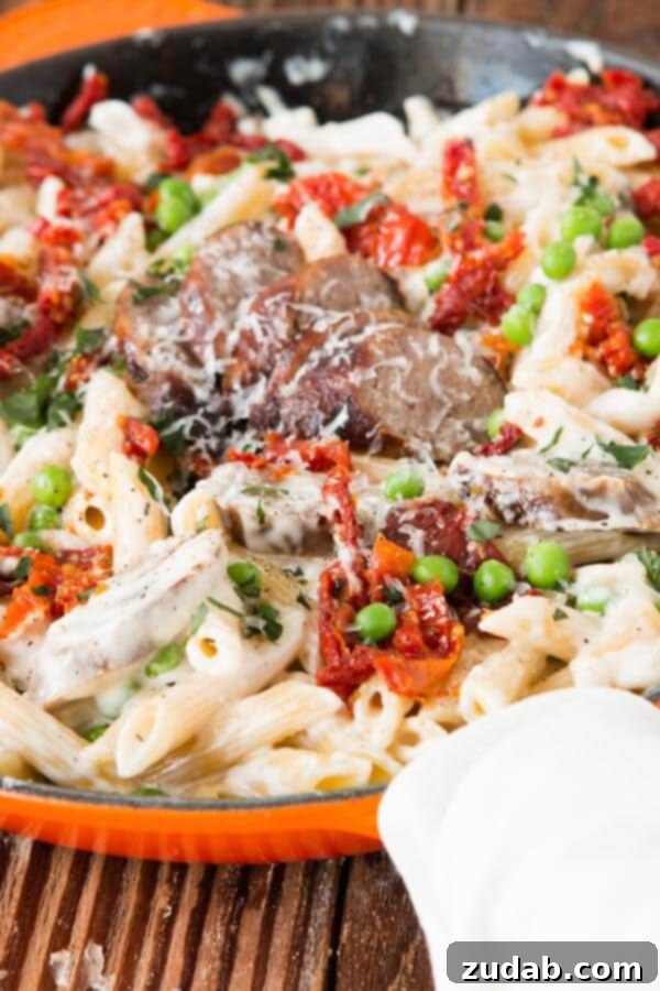 Creamy Sausage Alfredo Pasta - A Family Favorite Recipe Close-up of creamy sausage Alfredo pasta dish, showing penne pasta, sliced sausages, and rich white sauce with subtle hints of sun-dried tomatoes