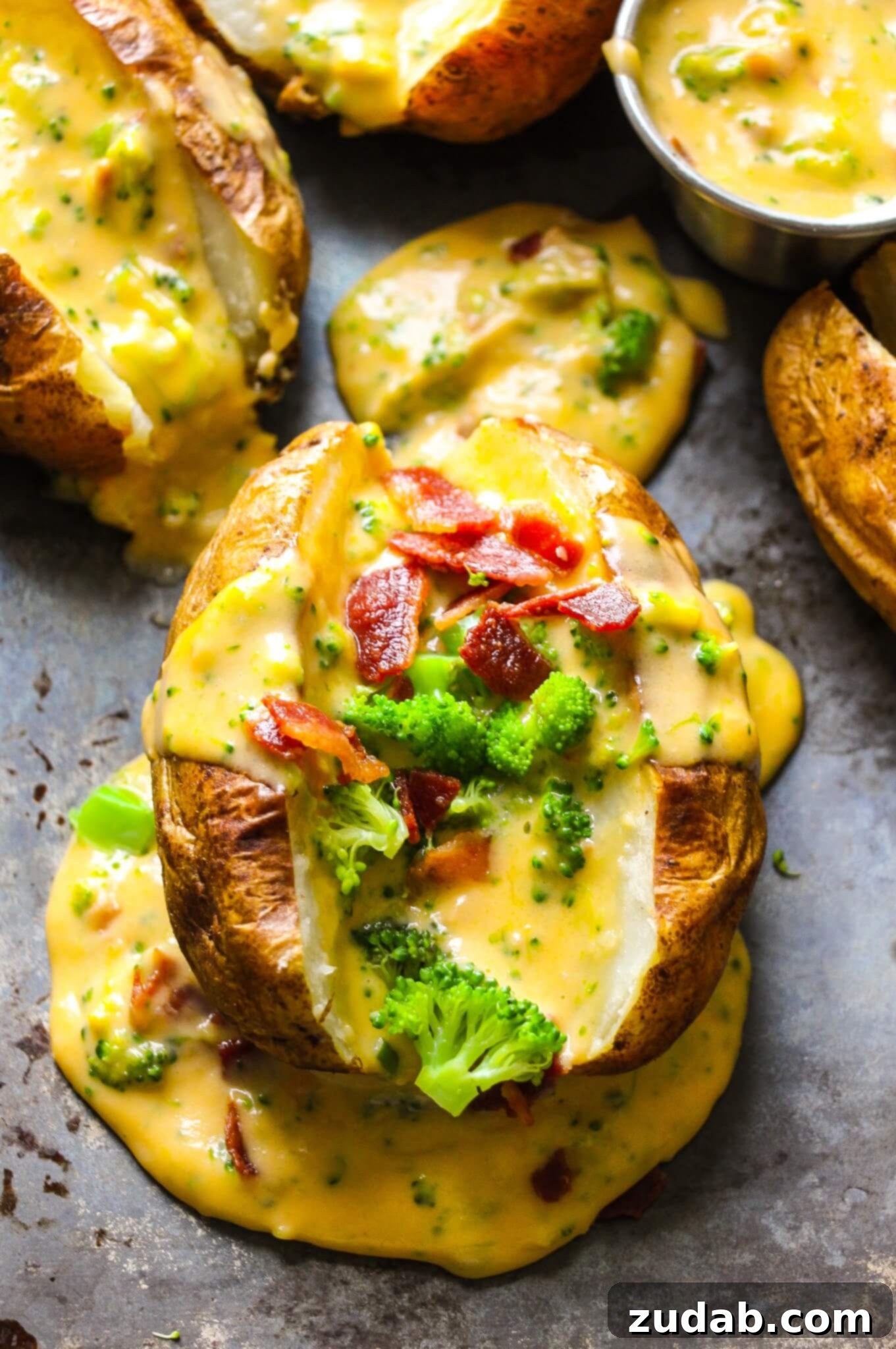 Loaded Baked Potatoes with Homemade Cheese Sauce a photo of a baked potato sliced in half, open, and stuffed with broccoli, bacon crumbles and topped with homemade cheese sauce.
